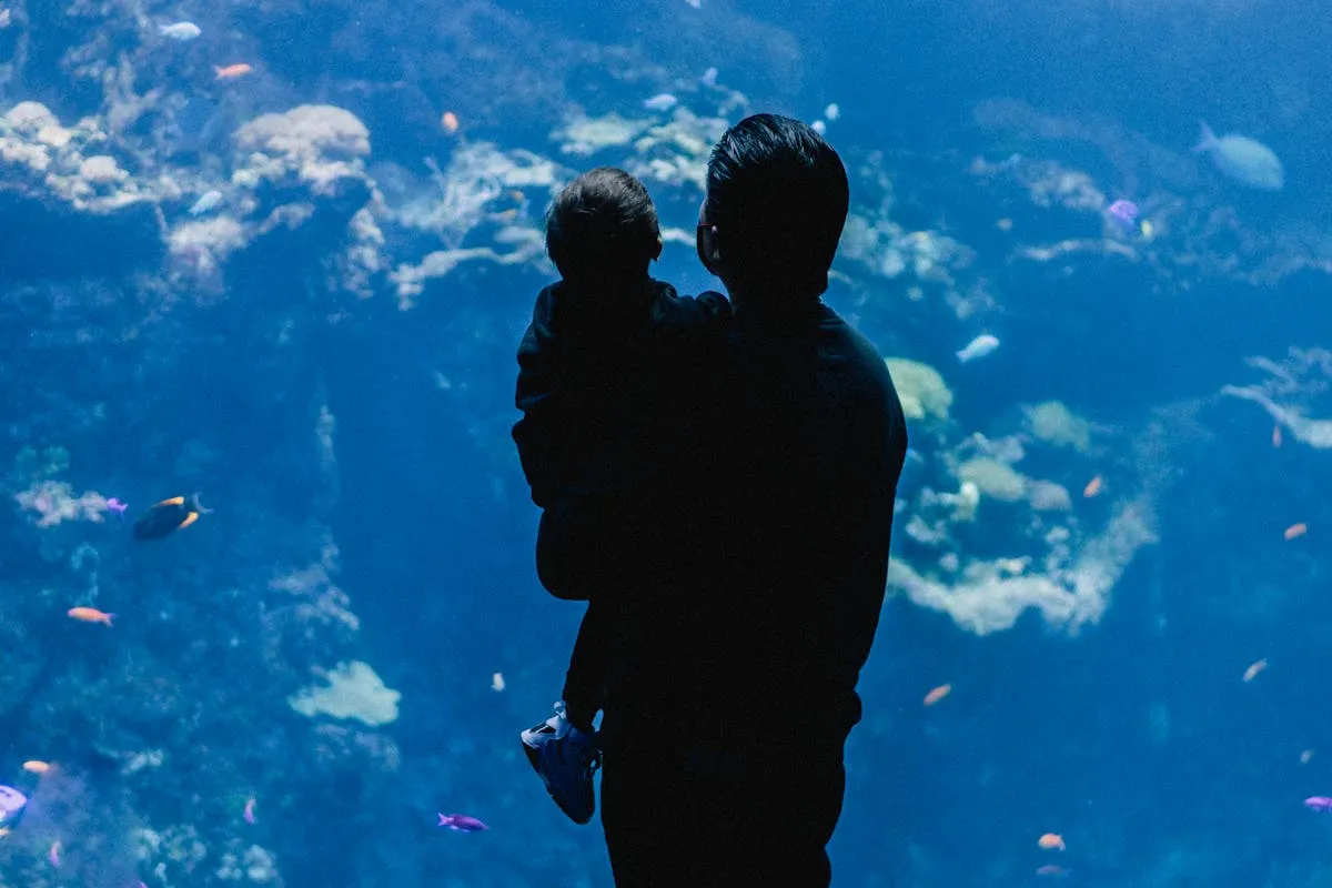 Father and child watching fish at the aquarium