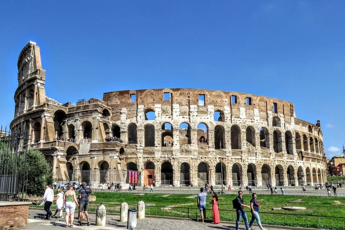 Turistas visitando o Coliseu de Roma sob o sol de verão